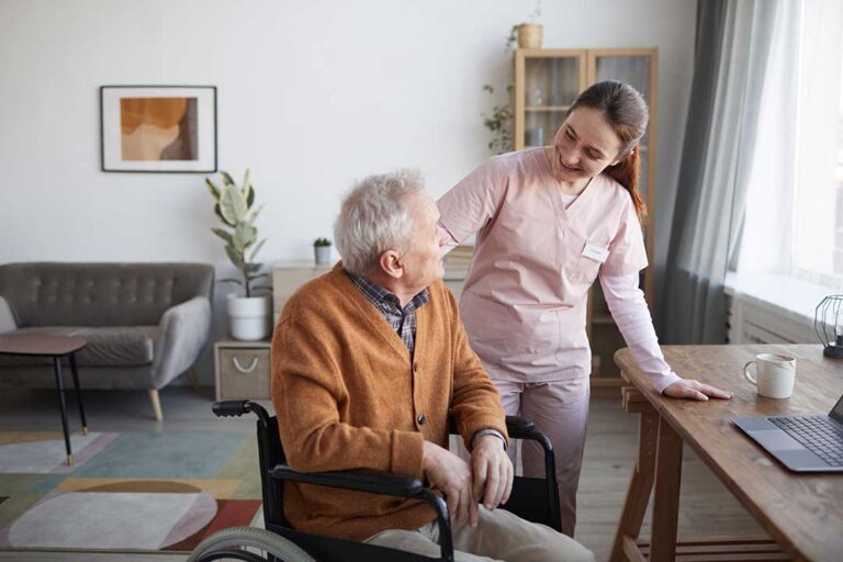 A family sits together with an elderly loved one in a bright, comfortable living room, smiling and talking.